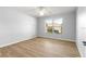 Bedroom featuring a ceiling fan, a window showcasing the surrounding neighborhood, and light wood flooring at 9287 Sw 91St Court Rd, Ocala, FL 34481