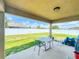 A covered back patio has neutral colors, a table, chairs, and a view of the fenced backyard at 9677 Sw 56Th Cir, Ocala, FL 34476