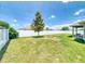A spacious backyard features a well-kept lawn, a white fence, a young magnolia tree, and a covered patio at 9677 Sw 56Th Cir, Ocala, FL 34476