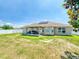 A spacious yard shows the home's back facade, covered patio, vinyl fence, and solar panels on the roof at 9677 Sw 56Th Cir, Ocala, FL 34476