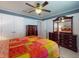 Cozy bedroom featuring a ceiling fan, wood floors, and matching dark wood dressers and mirror at 9677 Sw 56Th Cir, Ocala, FL 34476