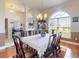 View of a dining area showcasing wood flooring, a large window, and a chandelier fixture at 9677 Sw 56Th Cir, Ocala, FL 34476