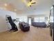 Spacious living room featuring plush carpeting, comfortable leather seating, and a ceiling fan at 9677 Sw 56Th Cir, Ocala, FL 34476