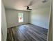 Bedroom with a ceiling fan, wood-look flooring, white walls, and a window overlooking the backyard at 1057 Nw 68Th Pl, Ocala, FL 34474