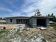 Unfinished single-story home with a gray exterior, attached garage, and construction debris in the yard at 1057 Nw 68Th Pl, Ocala, FL 34474