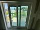 View through sliding glass doors to backyard with overgrown grass and partially obstructed views by mini blinds at 1057 Nw 68Th Pl, Ocala, FL 34474