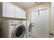 Well-equipped laundry room featuring a washer, dryer, storage cabinets and a white door leading to the outside at 13786 Se 88Th Ct, Summerfield, FL 34491