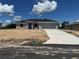 New construction home with a gray facade, a two-car garage, and a concrete driveway in a partially landscaped yard at 15419 Sw 65Th Terrace Rd, Ocala, FL 34473