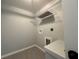 Small laundry room features gray walls, a metal shelf, gray tile floor, and hook ups for a washer and dryer at 15419 Sw 65Th Terrace Rd, Ocala, FL 34473