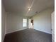 Bright, carpeted bedroom featuring neutral walls, vaulted ceilings, and a view into the kitchen area at 15833 Se 97Th Ter, Summerfield, FL 34491