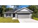 Image shows single-story home with gray siding, a two-car garage, and well-maintained landscaping at 15833 Se 97Th Ter, Summerfield, FL 34491