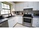 Well-lit kitchen features white cabinetry, stainless steel appliances, herringbone backsplash, and gray countertops at 2406 Se 40Th Street Rd, Ocala, FL 34480