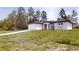 Single-story house with a long driveway, garage, modern elevation, amid tall trees and grass at 2438 Sw 165Th Street Rd, Ocala, FL 34473