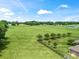 Aerial view of a large, green pasture with scattered trees, a fence, and a view of a home at 2540 Ne 120Th St, Anthony, FL 32617