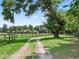 Scenic tree-lined driveway provides a picturesque entrance to the home and sprawling property beyond the wooden fence at 2540 Ne 120Th St, Anthony, FL 32617