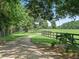 Gravel driveway winding through mature trees and past a wooden fence, offering a peaceful approach at 2540 Ne 120Th St, Anthony, FL 32617