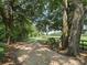 Long gravel driveway framed by mature trees and a wooden fence, showcasing a picturesque rural property at 2540 Ne 120Th St, Anthony, FL 32617