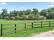 Ranch-style home showcases manicured landscaping and expansive green lawn surrounded by a wooden fence for privacy at 2540 Ne 120Th St, Anthony, FL 32617