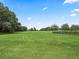Expansive green pasture with mature trees and fencing under a clear blue sky, offering a serene rural view at 2540 Ne 120Th St, Anthony, FL 32617