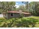 Ranch-style home with a red metal roof and a well-maintained lawn and mature trees at 4010 Sw 7Th Avenue Rd, Ocala, FL 34471