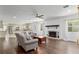 Open living room featuring a decorative fireplace, hardwood floors, and adjoined, sun-lit kitchen at 4010 Sw 7Th Avenue Rd, Ocala, FL 34471