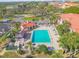 Aerial view of a square pool with palm trees, lounge chairs, and buildings with terra cotta roofs at 420 Bouchelle Dr # 204, New Smyrna Beach, FL 32169
