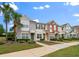 View of townhomes featuring colorful exteriors, a sidewalk and mature landscaping with palm trees at 4412 Sw 49Th Ave, Ocala, FL 34474