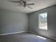 Bright bedroom with neutral walls, wood-look floors, ceiling fan, and large window offering scenic views at 5787 Nw 58Th Ter, Ocala, FL 34482