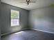 Bright bedroom with modern gray wood-look tile flooring, a ceiling fan, and a window allowing natural light at 5787 Nw 58Th Ter, Ocala, FL 34482