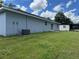 Home's exterior back view showcases its well-kept lawn, sliding glass door, and durable siding at 5787 Nw 58Th Ter, Ocala, FL 34482