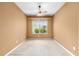 This empty room features neutral-colored walls, carpet, a window and ceiling fan at 6651 Sw 93Rd Ct, Ocala, FL 34481