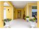 Inviting front porch featuring decorative plants and a welcoming entrance to a charming yellow home at 7641 Sw 63Rd Lane Road, Ocala, FL 34474