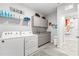 Bright laundry room with gray cabinets, modern appliances, and access to another room at 7641 Sw 63Rd Lane Road, Ocala, FL 34474