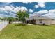 View of the spacious backyard with white fence, lush lawn, playground and covered patio at 8170 Sw 56Th Avenue Rd, Ocala, FL 34476