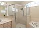 Bright bathroom featuring glass shower, a large mirror above the sink, and tiled tub with tile surround at 8170 Sw 56Th Avenue Rd, Ocala, FL 34476