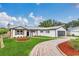 Stylish white home featuring wood shutters, a red brick driveway, and well-maintained landscaping at 8622 Baylor Cir, Orlando, FL 32817