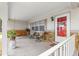 Welcoming front porch with rocking swing, chairs, stone accents, and a red front door at 8874 Sw 95Th St # E, Ocala, FL 34481