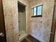 Shower and commode area with patterned wallpaper, shower and window under natural light at 8901 Sw 103Rd Ln, Ocala, FL 34481