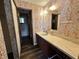 A bathroom featuring patterned wallpaper, a vanity with sink, mirror and view into the shower area at 8901 Sw 103Rd Ln, Ocala, FL 34481
