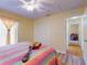 This bright bedroom features a guitar on the bed, a ceiling fan and an exit hallway at 9325 Sw 125Th Court Rd, Dunnellon, FL 34432