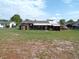 Large grassy backyard is partially barren in areas, backs up to the home and a red car at 9430 Sw 102Nd Pl, Ocala, FL 34481