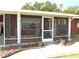 Close-up view of the screened-in porch with outdoor seating, potted plants, and a welcoming front entrance at 9430 Sw 102Nd Pl, Ocala, FL 34481