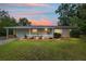 Inviting single-story home with lush green lawn and cozy front porch highlighted by a beautiful sunset at 9940 Sw 101St Pl, Ocala, FL 34481