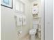 Toilet room features a modern toilet, cabinet, neatly folded towels, window with blinds, and a tiled floor at 9940 Sw 101St Pl, Ocala, FL 34481