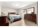 Comfortable bedroom with wooden furniture set, light tile floor, and bright window at 16220 Sw 19Th Avenue Rd, Ocala, FL 34473