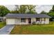Front elevation of a cozy home with a driveway, shutters, and a red door at 2140 Ne 40Th St, Ocala, FL 34479