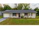 Single-story home featuring a red door, window shutters, and a well-manicured front lawn at 2140 Ne 40Th St, Ocala, FL 34479