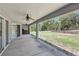 Back porch with fan overlooking wooded backyard and firewood at 22189 Sw Neptune Blvd, Dunnellon, FL 34431