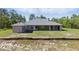Rear exterior view of the home showing the large backyard and brick retaining wall at 22189 Sw Neptune Blvd, Dunnellon, FL 34431