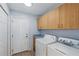 Laundry room with white front load washer and dryer with overhead cabinets at 22189 Sw Neptune Blvd, Dunnellon, FL 34431